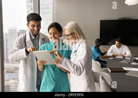 Positive Gesundheitspersonal in weißen Uniformmänteln mit digitaler Tablette Stockfoto