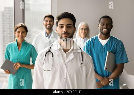 Positiv attraktiver junger arabischer Arzt in Uniform mit Blick auf die Kamera Stockfoto