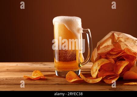 Schließen Sie das Bierglas und die Kartoffelchips über braun Stockfoto