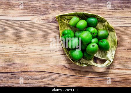 Ein Haufen Mini-Kiwis auf einer goldenen Metallplatte liegen flach auf einem hölzernen Hintergrund isoliert Stockfoto