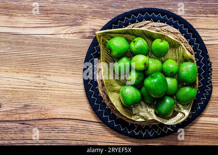 Ein Haufen Mini-Kiwis auf einer goldenen Metallplatte auf einer runden Strohmatte isoliert Stockfoto