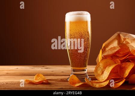 Schließen Sie das Bierglas und die Kartoffelchips über braun Stockfoto