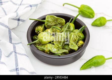 Gebratene Padron-Paprika in einer Schüssel auf Marmortisch Stockfoto