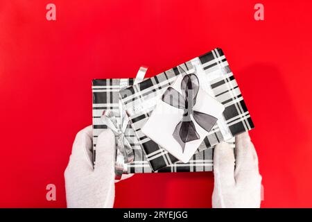 Weihnachtsmann mit Handschuhen, der ein Weihnachtsgeschenk hält Stockfoto