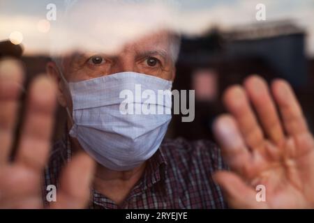 Älterer kaukasischer Mann mit handgefertigter Schutzmaske Stockfoto