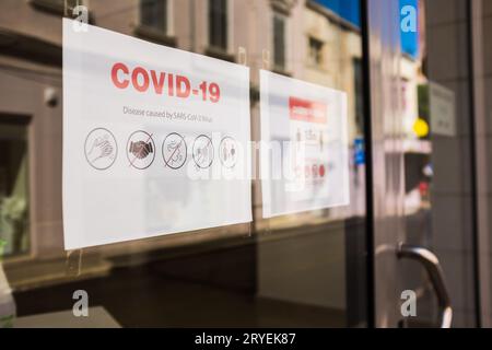 Hinweis zu COVID-19-Sicherheitsmaßnahmen am Lagerfenster Stockfoto