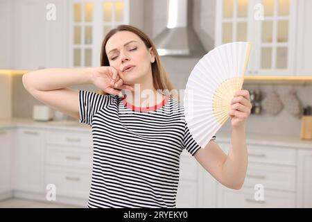 Frau mit Handventilator leidet unter Hitze in der Küche Stockfoto
