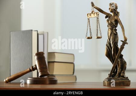 Figur der Lady Justice, Hammer und Bücher auf Holztisch im Innenbereich. Symbol der gerechten Behandlung nach dem Gesetz Stockfoto