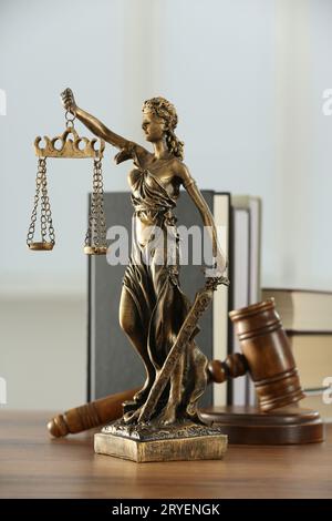 Figur der Lady Justice, Hammer und Bücher auf Holztisch im Innenbereich. Symbol der gerechten Behandlung nach dem Gesetz Stockfoto