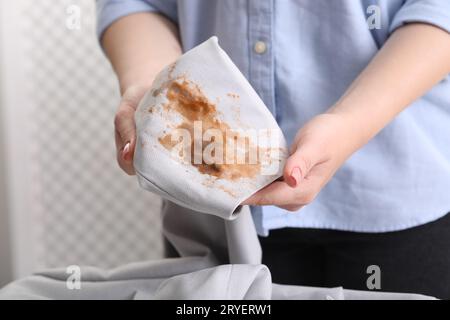 Frau zeigt Flecken vom Kaffee auf der Jacke vor verschwommenem Hintergrund, Nahaufnahme Stockfoto