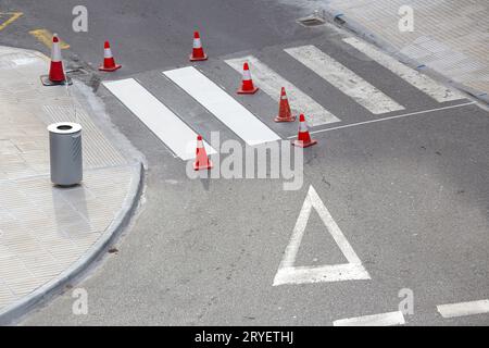 Wartungskonzept für Straßenlackierung. Weiße Straßenlinien auf Fußgängerübergängen und Straßenkegel auf der Stadt Stockfoto