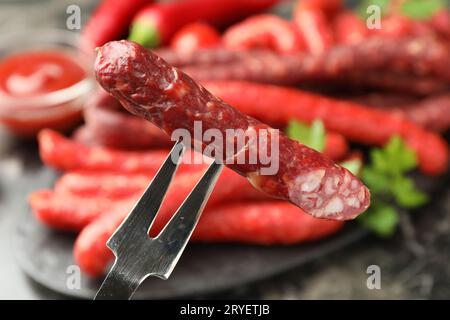 Gabel mit dünner, trocken geräucherter Wurst über dem Tisch, Nahaufnahme Stockfoto