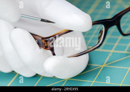 Optiker Hände in Handschuhen Brillenreparatur mit einem Werkzeug Stockfoto