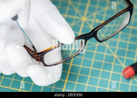 Optiker Hände in Handschuhen Brillenreparatur mit einem Werkzeug Stockfoto