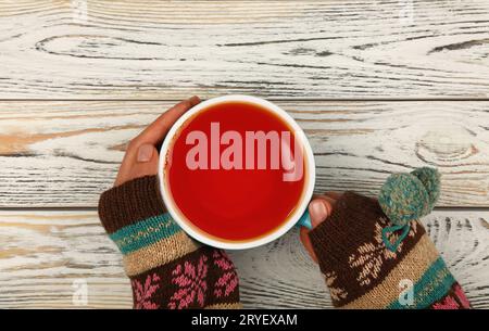 Frauenhände halten eine volle Tasse schwarzen Tee Stockfoto