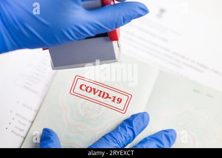 Der britische Grenzschutzbeamte trägt blaue Schutzhandschuhe, die COVID-19 auf das Dokument auftragen Stockfoto