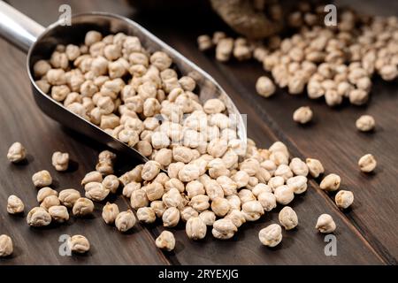 Ungekochte Kichererbsen auf Schaufel auf rustikalem Holztisch. Rustikales Stillleben Stockfoto