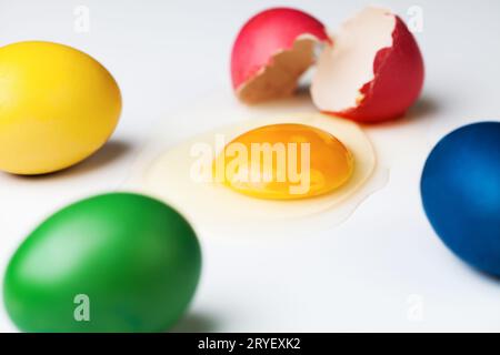 Bunt bemalte Eier mit verschüttetem Eigelb von geknacktem Stockfoto