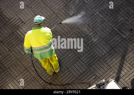 Arbeiter, die an sonnigen Tagen einen Straßenweg mit Hochdruckwasserstrahlmaschine reinigen. Speicherplatz kopieren. Draufsicht Stockfoto