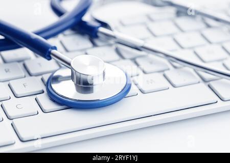 Nahaufnahme eines Stethoskops auf der Computertastatur auf dem weißen Schreibtisch. Online-Gesundheitsfürsorge oder Telemedizin-Konzept. Medizinischer Hintergrund Stockfoto