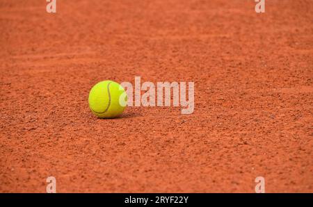 Gelber Tennisball auf rotem Lehmboden Stockfoto