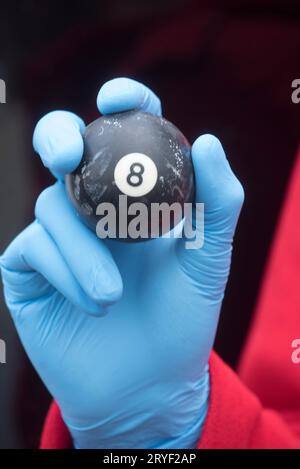 Person, die den schwarzen Ball mit der Nummer acht in der Hand hält Stockfoto