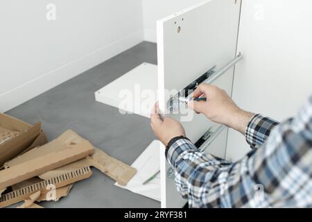 Nahaufnahme eines Mannes Montage eines Schubladenschiebers Möbel mit einem Schraubendreher Stockfoto