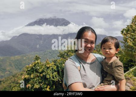 Porträtbild der asiatischen chinesischen Mutter mit glücklichen 1-2 Jahren mit dem größten Mount Kinabalu von Sabah, Borneo mit klarem blauen Himmel Stockfoto