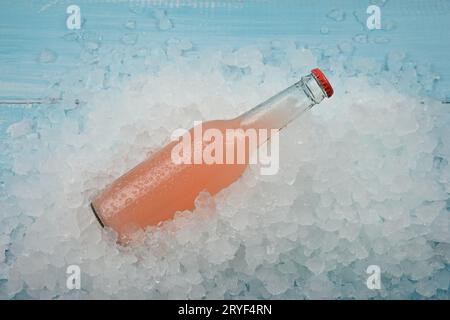 Eine Glasflasche rosafarbenes Getränk auf zerstoßenem Eis Stockfoto