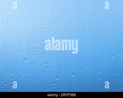 Regentropfen auf Glasfenster über grauem und blauem Himmel Stockfoto