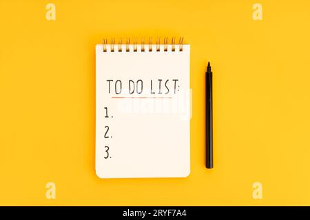 To-do-Liste in Spiralnotepad isoliert auf gelbem Hintergrund. Draufsicht Stockfoto