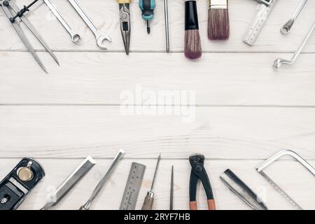Rahmen von Arbeitswerkzeugen auf weißem Holztisch mit Kopierraum. Draufsicht Stockfoto