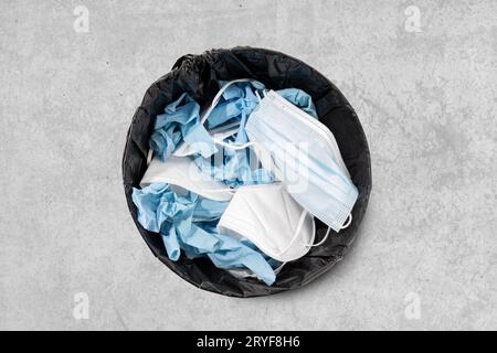 Mülleimer voll mit gebrauchter Gesichtsmaske und Schutzhandschuhen. Covid-19 Schutzabfallkonzept. Draufsicht Stockfoto