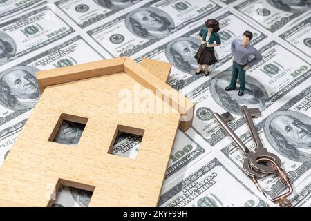 Investition in ein Hauskonzept. Immobilienpreise. Spielzeughaus und Figurenpaar auf Dollar-Banknote Hintergrund Stockfoto