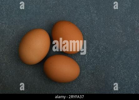 Drei braune Hühnereier auf dunklem Tisch Stockfoto