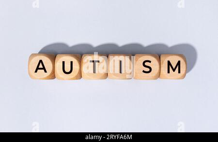 Autismus-Wort auf Holzblock isoliert auf grauem Hintergrund Stockfoto