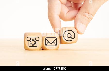 Kontaktieren Sie uns Icons auf Holzblöcken. Hand mit einem Würfel mit Kommunikationssymbol. Speicherplatz kopieren Stockfoto
