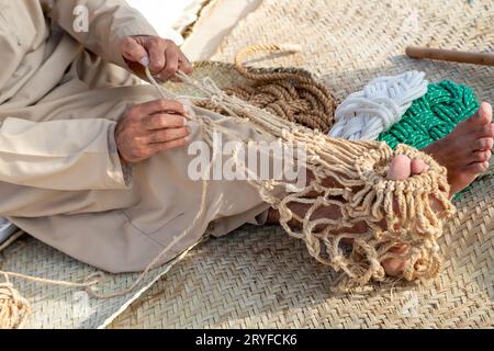 Der alte Mann strickt traditionelles Fischernetz, Hände im Rahmen Stockfoto