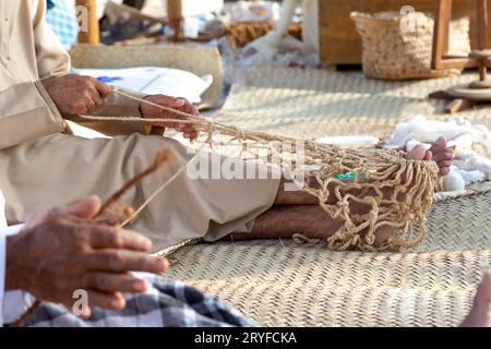 Der alte Mann strickt traditionelles Fischernetz, Hände im Rahmen Stockfoto