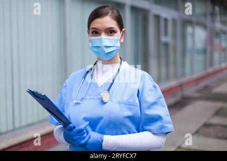 Besorgte junge Ärztin, die vor dem Krankenhaus steht Stockfoto