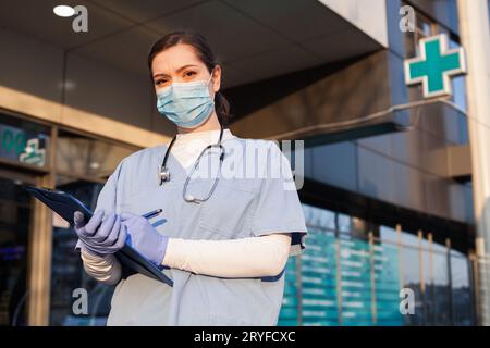 Weibliche Ärztin steht vor der Eingangstür des Krankenhauses Stockfoto