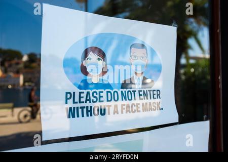 BITTE BETRETEN SIE DAS HOTEL NICHT OHNE Ein Schild mit Einer GESICHTSMASKE an der Glastür des Geschäfts oder Büros Stockfoto