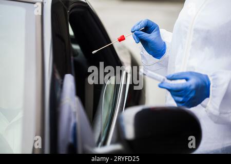 Die Hände des medizinischen Mitarbeiters in Handschuhen, die das PCR-Testkit im mobilen Testzentrum halten Stockfoto