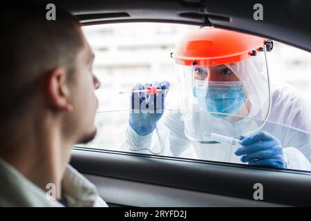 Weibliche Ärztin nimmt PCR-Tupfer-Probe von jungen männlichen Patienten Stockfoto