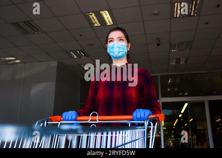 Eine junge Frau, die einkaufen geht und eine Schutzmaske trägt Stockfoto