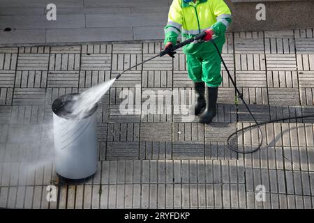 Kehrmaschine Reinigung eines Abfallbehälters auf dem Bürgersteig mit Hochdruck-Wasserstrahlmaschine. Straßenpflege Stockfoto