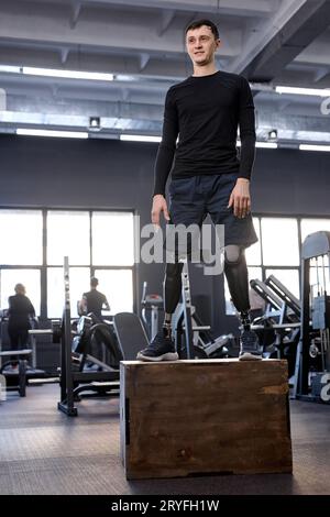 Selbstbewusster Brünette, der mit einer Fitnessbox in einem Fitnessstudio Sport treibt, Foto in voller Länge. Motivation, geben Sie niemals auf. Die Liebe zum Leben. Stärke Stockfoto