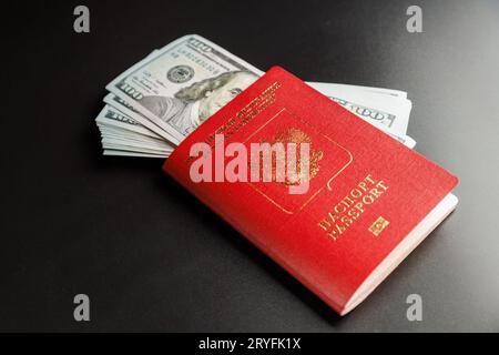 Russischer internationaler Pass mit eingefügten US-Dollar auf schwarzem Hintergrund Stockfoto