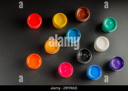Nahhintergrund geöffneter kleiner Gouache-Farbgläser auf schwarzer Oberfläche Stockfoto