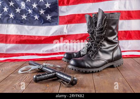 Handschellen aus Metall, schwarzer Knöchel und Polizei kleben in der Nähe der US-Flagge auf hölzernem Untergrund Stockfoto